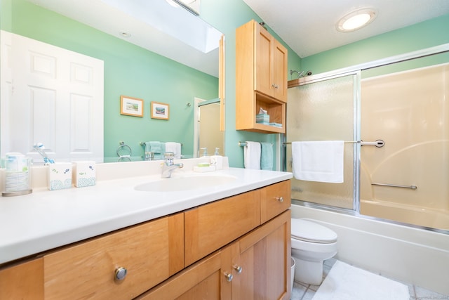 full bath with tile patterned floors, toilet, vanity, and bath / shower combo with glass door