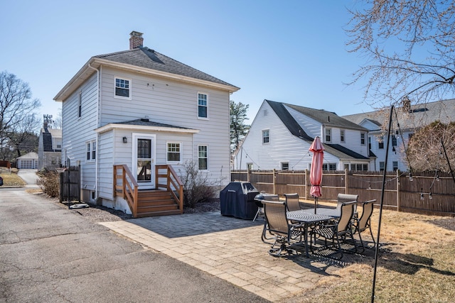 back of property featuring a patio area, a chimney, roof with shingles, and fence