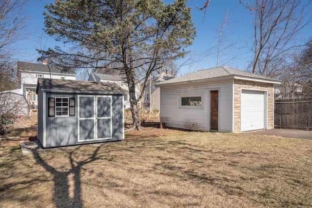 view of outdoor structure with an outbuilding, driveway, and fence