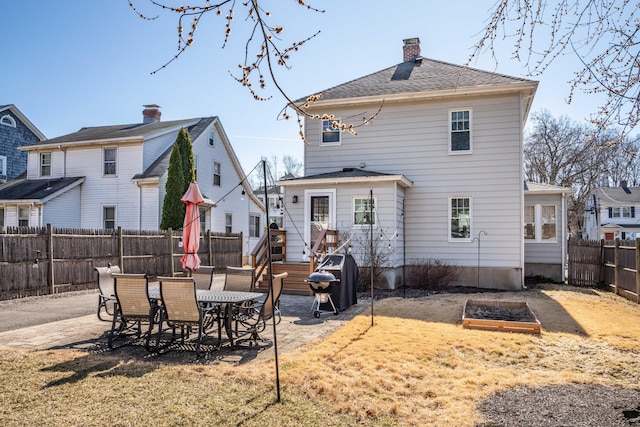 back of house featuring a patio area, a yard, a fenced backyard, and a chimney