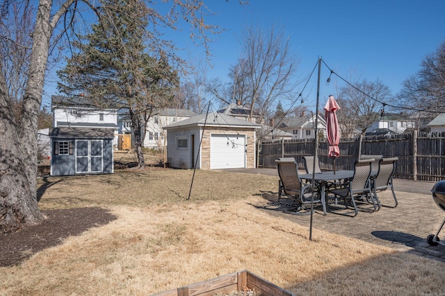 view of yard with a garage, an outbuilding, a storage shed, and fence