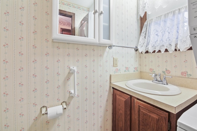 half bath featuring vanity and wallpapered walls