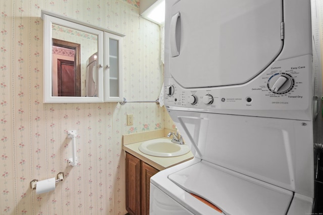 bathroom featuring wallpapered walls, vanity, and stacked washer and clothes dryer