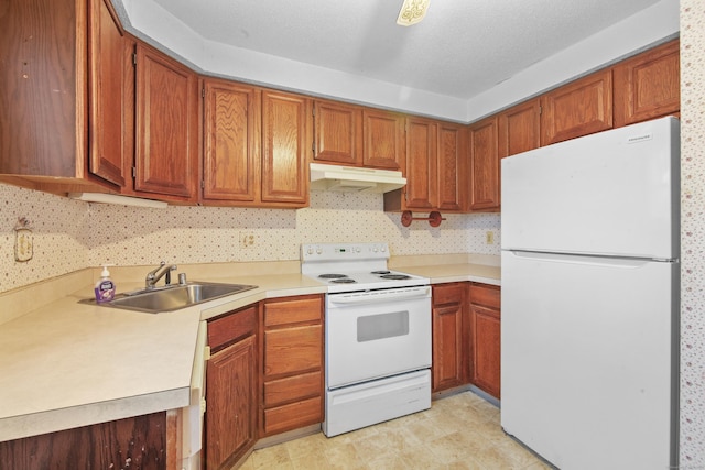 kitchen with white appliances, light countertops, under cabinet range hood, and a sink