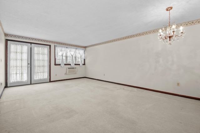 carpeted spare room featuring a notable chandelier, french doors, baseboards, and a wall mounted AC