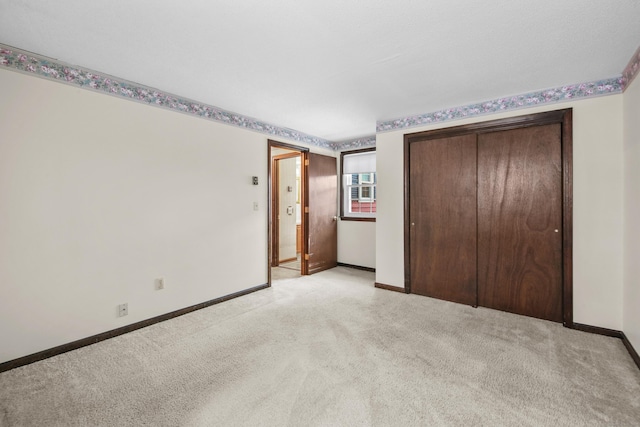 unfurnished bedroom with baseboards, light carpet, and a closet