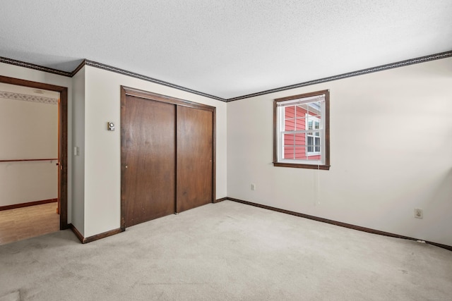 unfurnished bedroom with light carpet, a textured ceiling, crown molding, and a closet