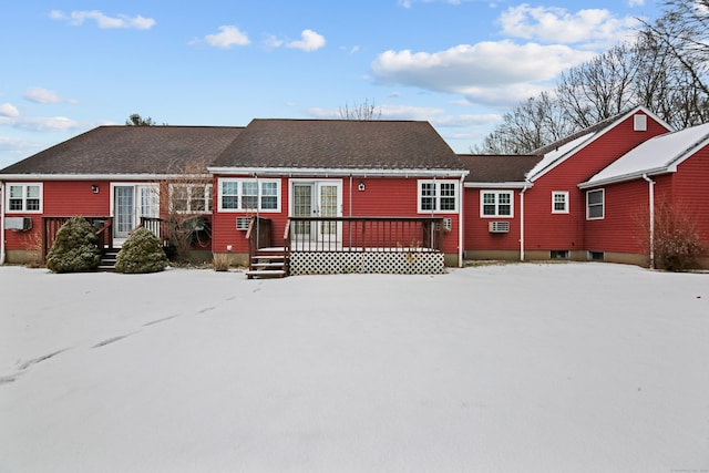 snow covered rear of property with a deck and a shingled roof