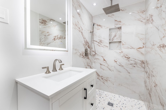 bathroom with recessed lighting, a marble finish shower, and vanity