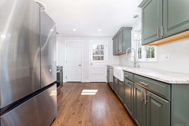 kitchen with a sink, light stone counters, recessed lighting, appliances with stainless steel finishes, and dark wood-style flooring