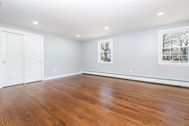 unfurnished bedroom with baseboards, baseboard heating, recessed lighting, a closet, and dark wood-style flooring