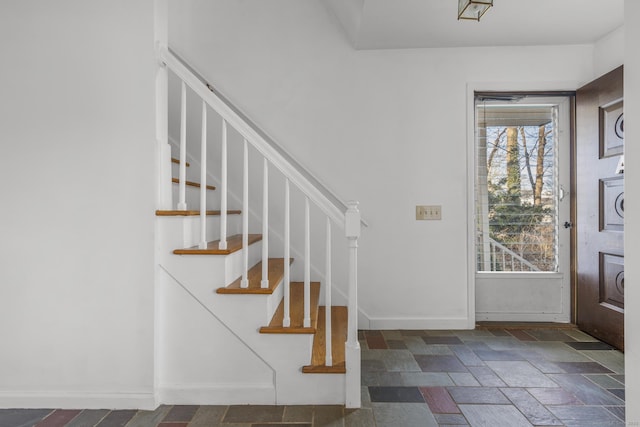 foyer entrance with stairway, plenty of natural light, baseboards, and stone tile flooring