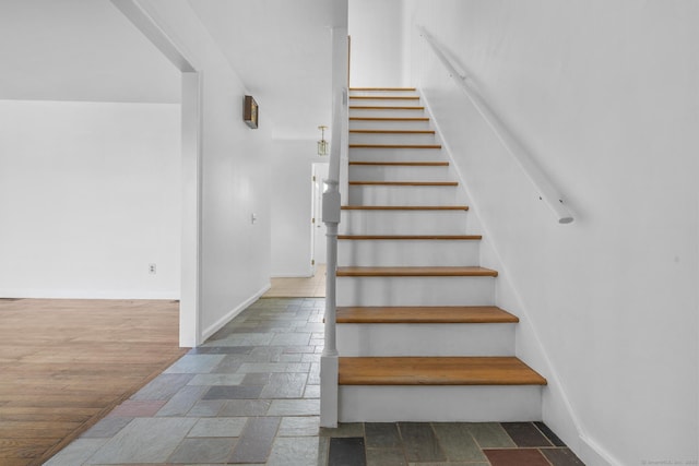 stairs featuring stone tile flooring and baseboards