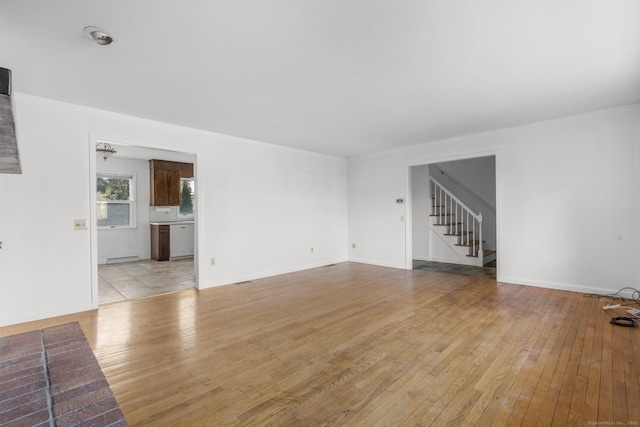 unfurnished living room with stairway and light wood finished floors