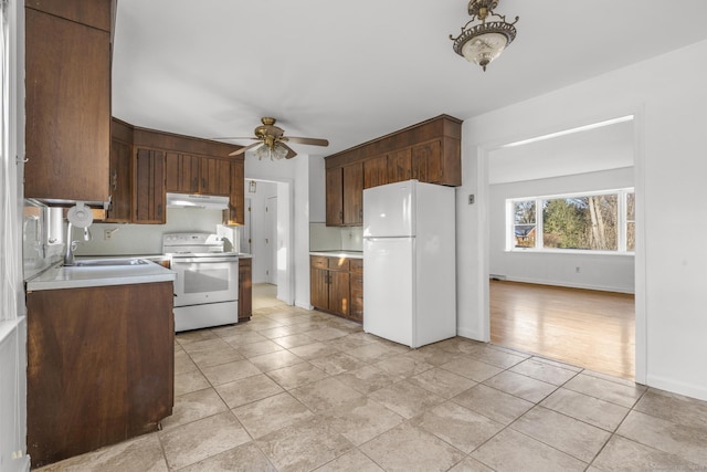 kitchen featuring a ceiling fan, under cabinet range hood, a sink, white appliances, and light countertops