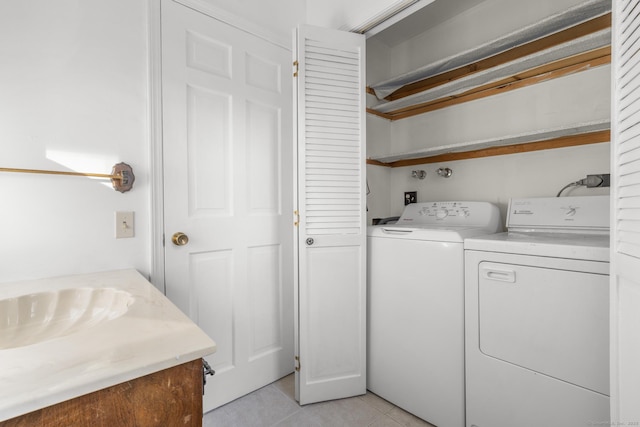 washroom with a sink, separate washer and dryer, light tile patterned flooring, and laundry area