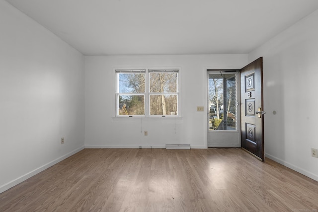 foyer with a baseboard heating unit, wood finished floors, and baseboards