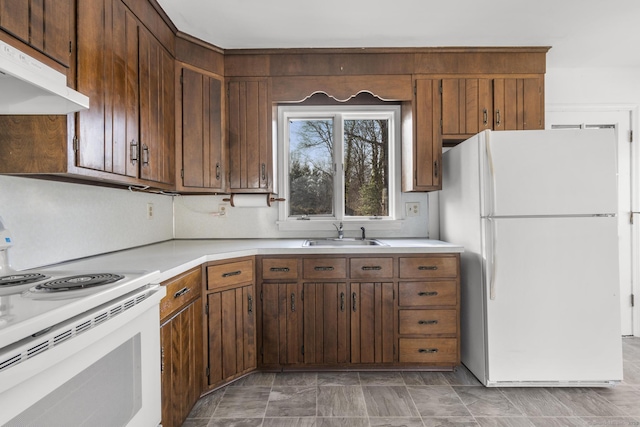 kitchen with white appliances, light countertops, under cabinet range hood, and a sink