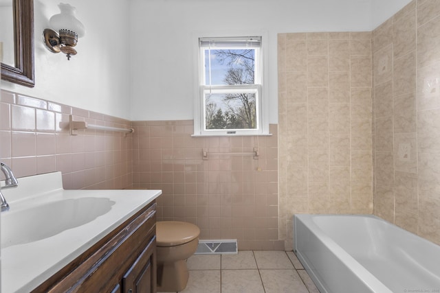 bathroom with visible vents, toilet, tile walls, tile patterned flooring, and vanity