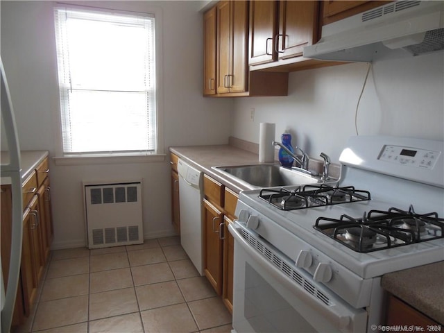 kitchen with radiator, under cabinet range hood, brown cabinets, white appliances, and a sink