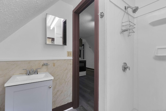 bathroom featuring a textured ceiling, walk in shower, and vanity