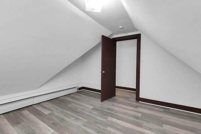 bonus room featuring a baseboard heating unit, baseboards, wood finished floors, and vaulted ceiling