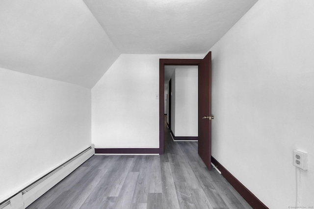 bonus room featuring a baseboard radiator, lofted ceiling, baseboards, and wood finished floors