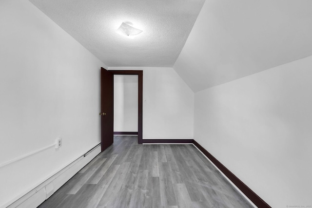 bonus room featuring lofted ceiling, a textured ceiling, wood finished floors, baseboards, and baseboard heating