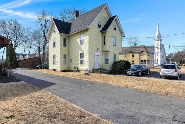 view of front of property with roof with shingles and a chimney