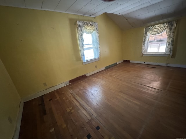 bonus room with lofted ceiling, plenty of natural light, baseboards, and wood-type flooring