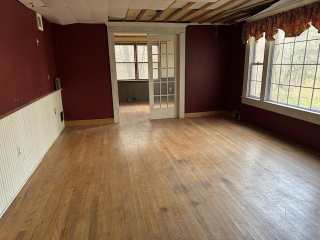 unfurnished room with a wainscoted wall, visible vents, and hardwood / wood-style flooring