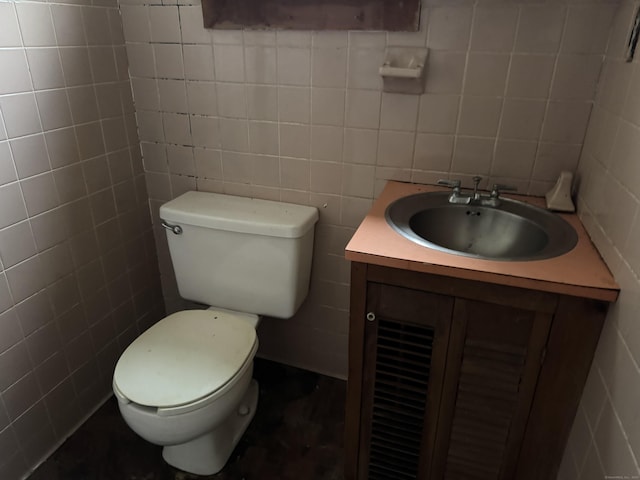 bathroom featuring toilet, tile walls, and vanity