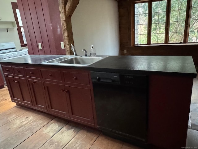 kitchen with a sink, black dishwasher, dark countertops, light wood-style floors, and white range with gas stovetop