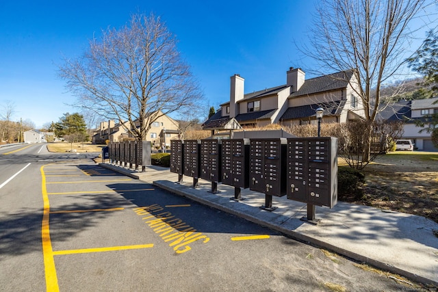 view of property's community with mail area, uncovered parking, and a residential view