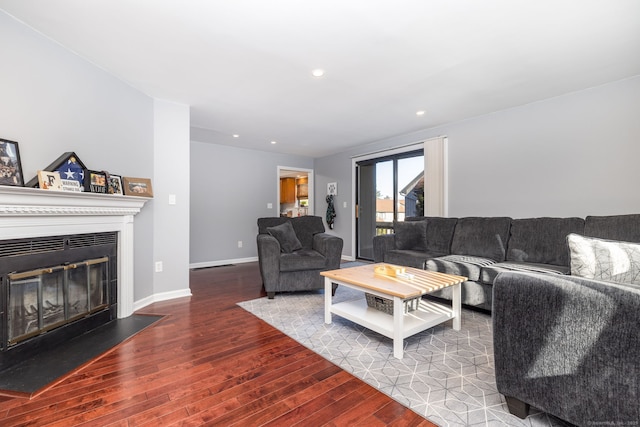 living area featuring a glass covered fireplace, recessed lighting, baseboards, and wood finished floors