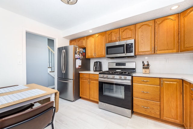 kitchen with light countertops, brown cabinetry, and appliances with stainless steel finishes