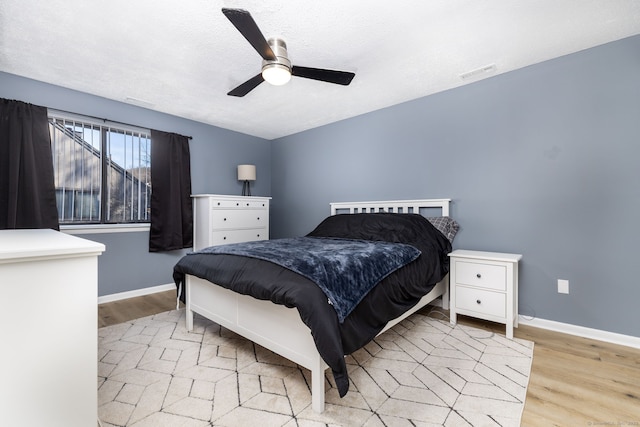 bedroom featuring a ceiling fan, light wood-style flooring, baseboards, and visible vents