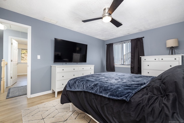 bedroom with visible vents, a textured ceiling, light wood-style floors, baseboards, and attic access