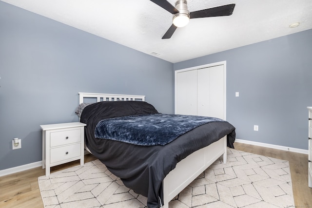 bedroom with baseboards, light wood-type flooring, and a closet