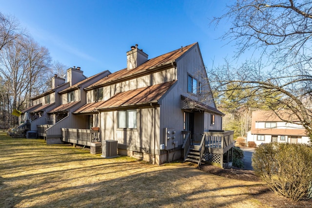 back of property with a wooden deck, a chimney, and a yard