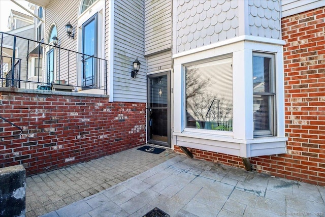 view of exterior entry with brick siding and a patio area