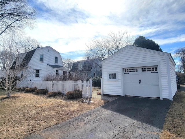 detached garage featuring aphalt driveway and fence