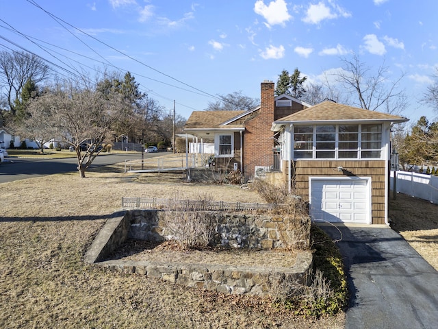 view of front facade featuring a shingled roof, fence, a chimney, driveway, and an attached garage