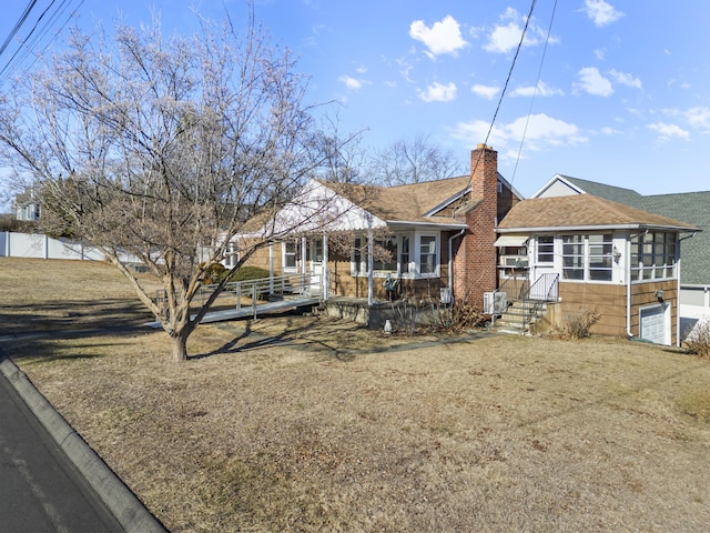 rear view of house featuring a yard, roof with shingles, and a chimney