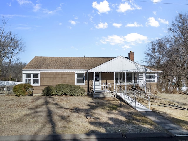 view of front of house with covered porch, a chimney, and a shingled roof