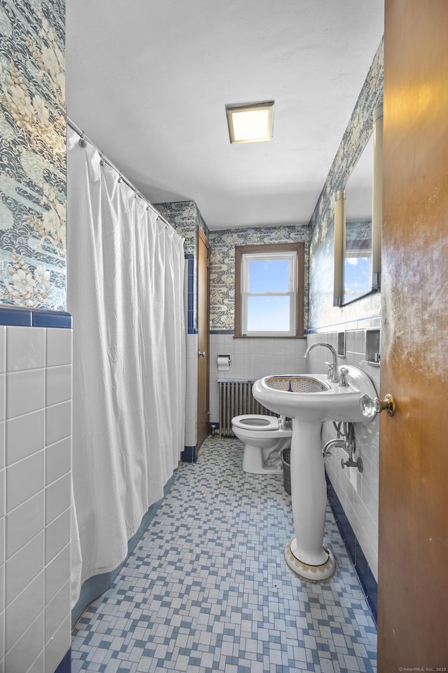 bathroom featuring wallpapered walls, tile walls, toilet, and a wainscoted wall