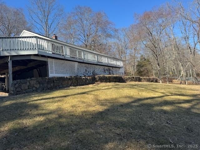 view of side of home featuring a wooden deck and a yard