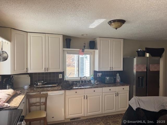 kitchen featuring a sink, backsplash, white cabinetry, stainless steel fridge, and dishwasher