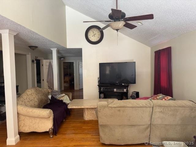 living area featuring wood finished floors, lofted ceiling, decorative columns, ceiling fan, and a textured ceiling