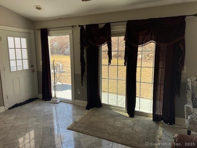 doorway to outside with baseboards and lofted ceiling